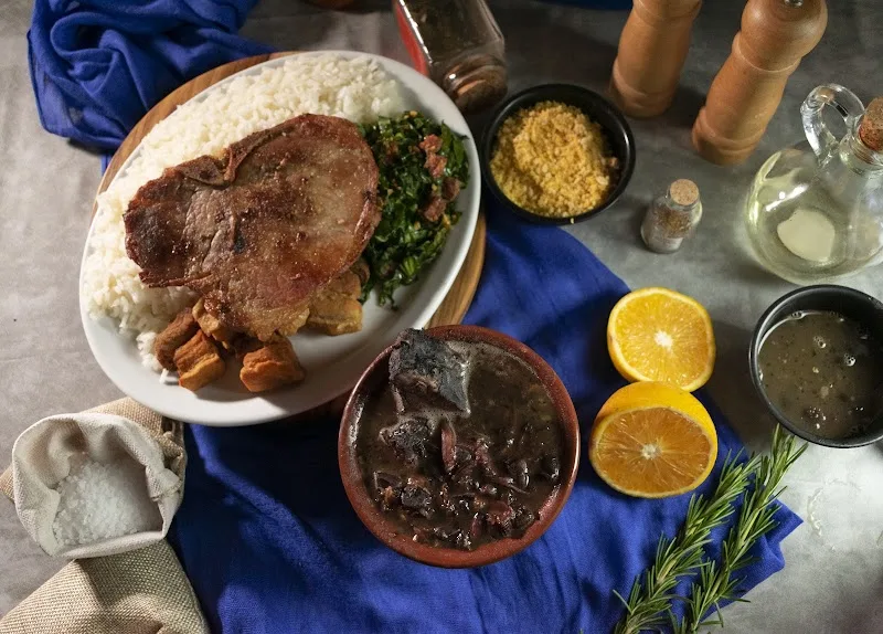 Bife com arroz, couve, farofa, feijão e laranja sobre toalha azul