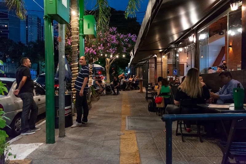 Mesas no terraço coberto ao longo da calçada, à noite